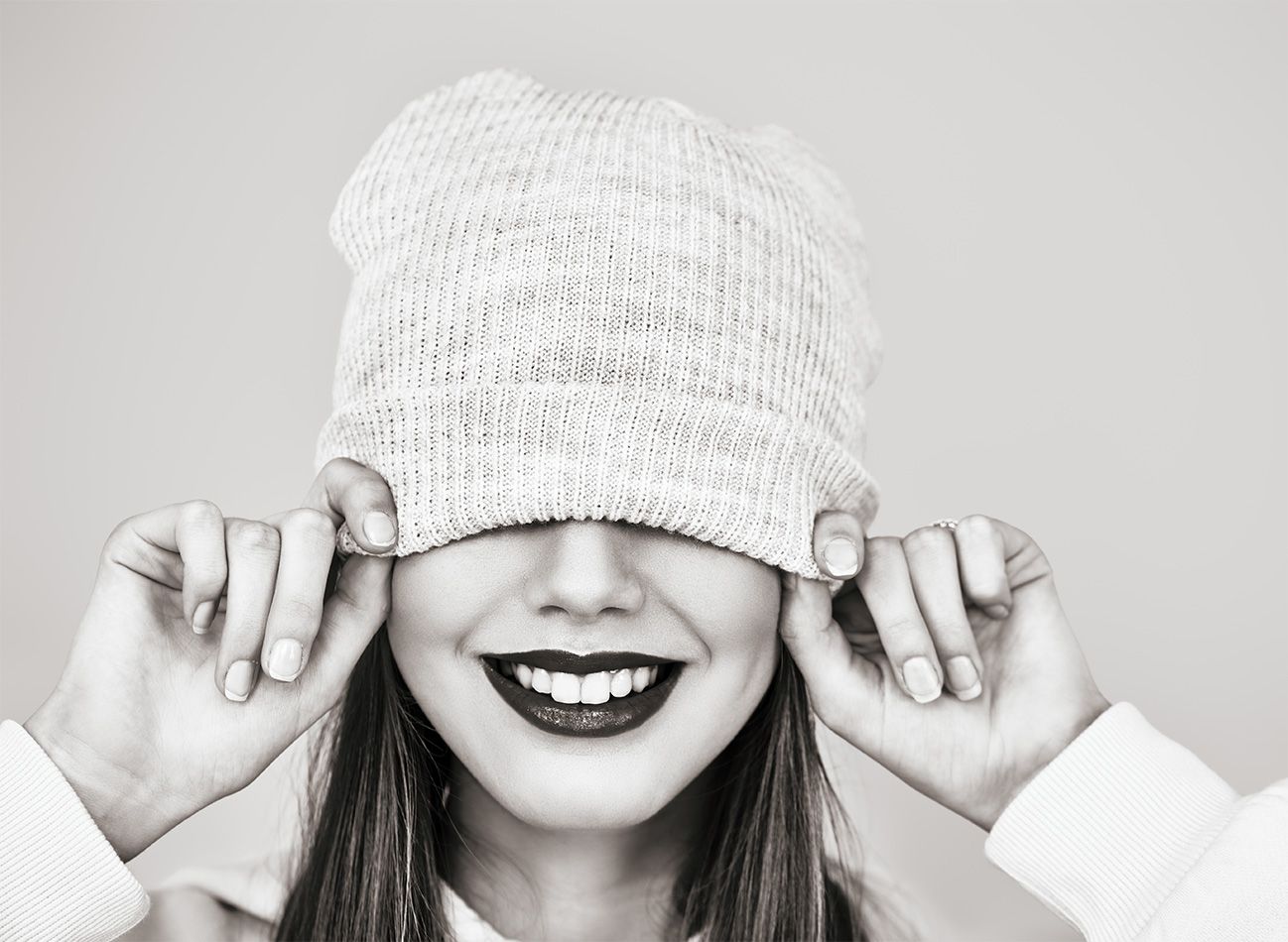 Lächelnde Frau, die eine Wollmütze über die Augen zieht