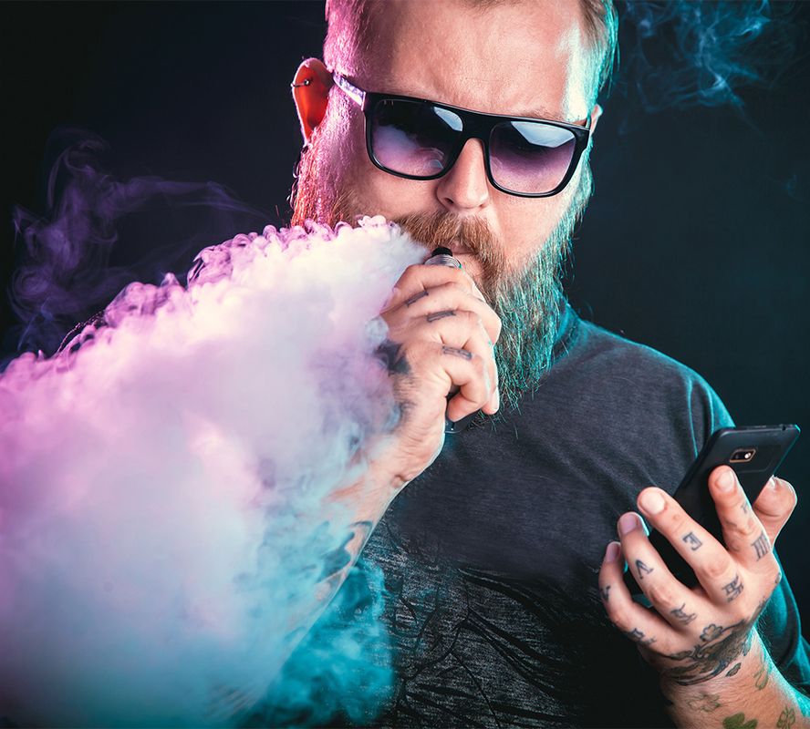 Mann mit Sonnenbrille mit Verdampfer in der Hand