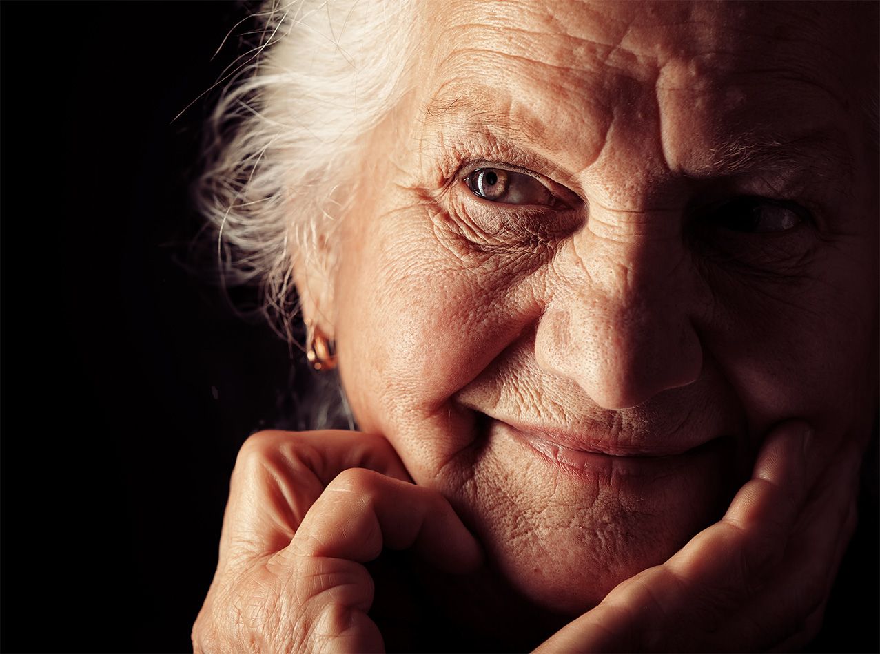 Nahaufnahme einer älteren Person vor dunklem Hintergrund