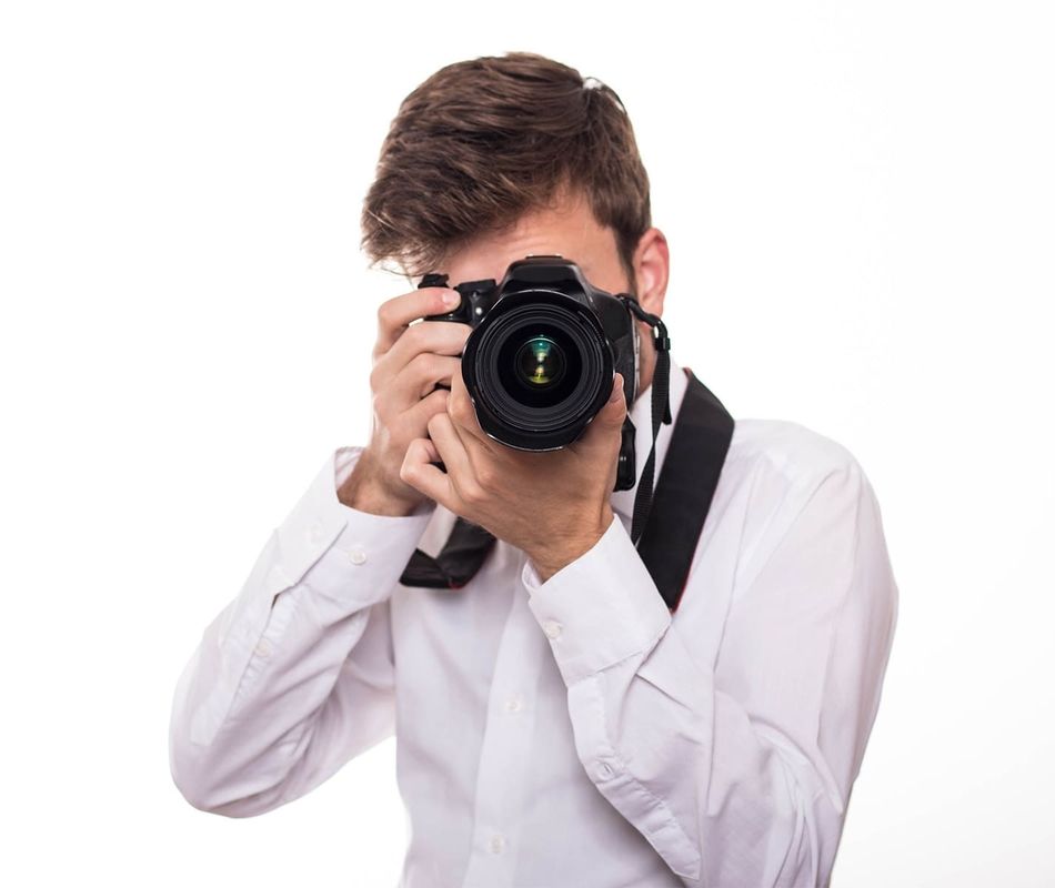 Mann in weißem Hemd schaut durch eine Fotokamera