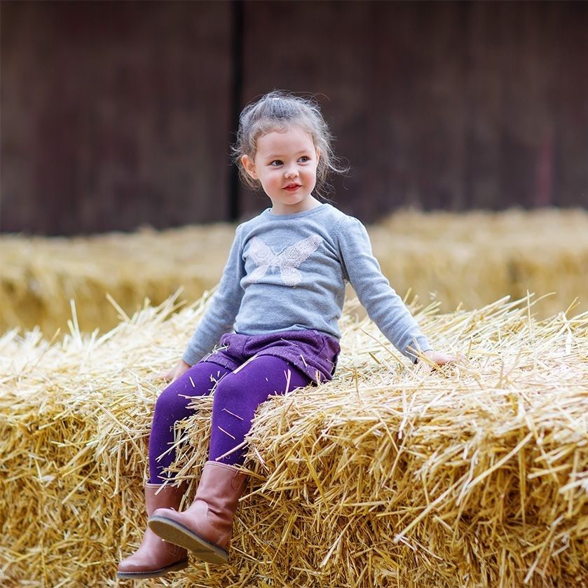 Kind, das auf einem Heuballen sitzt